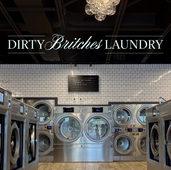 Dirty Britches Laundry sign on white tile above a bank of washers