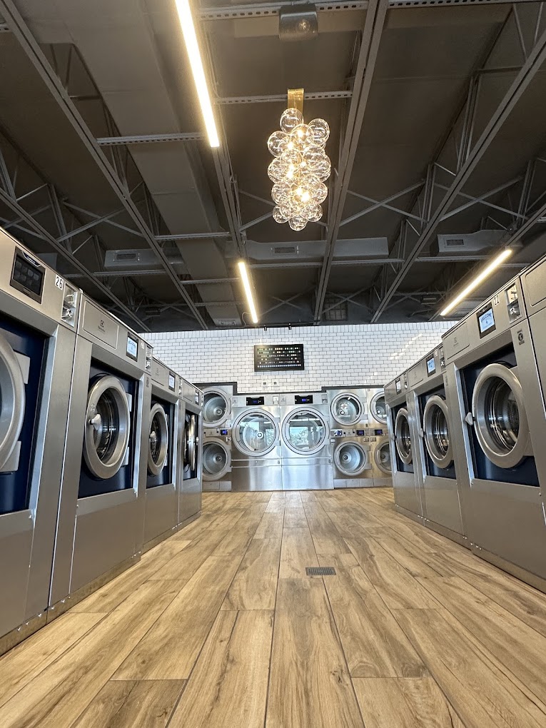 Bright aisle of stainless washers under a chandelier
