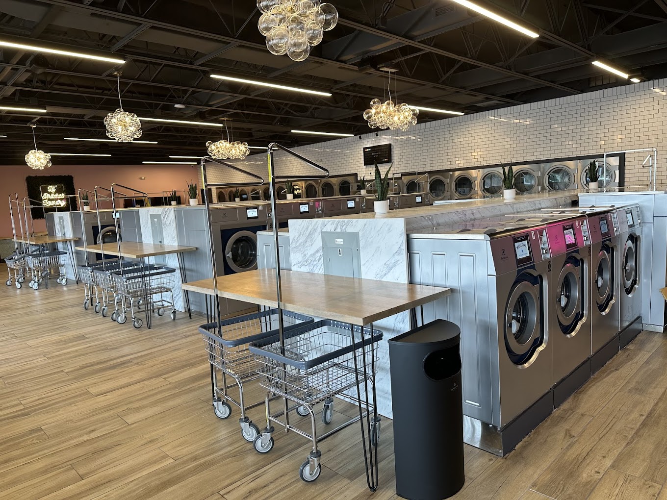 Crystal chandeliers above the folding tables and machine aisle at Dirty Britches Laundry